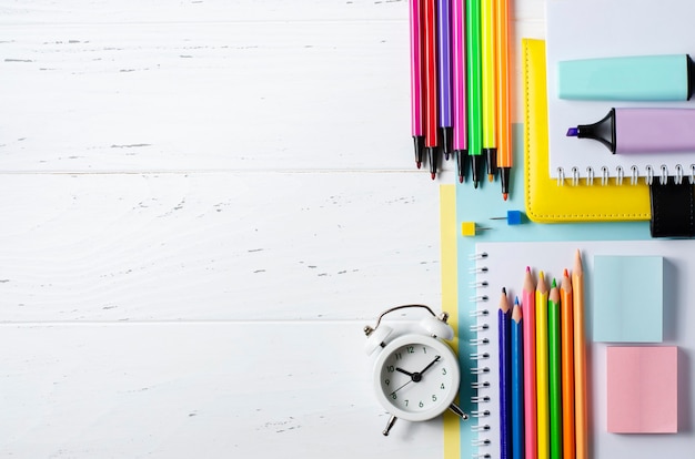 Acessórios infantis para estudo, criatividade e material de escritório em um fundo branco de madeira. de volta ao conceito de escola. copie o espaço.