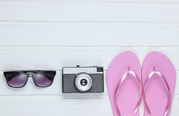 Acessórios para turismo de praia. Férias na praia. Flip-flops, câmera retro, óculos de sol no piso de madeira branco.