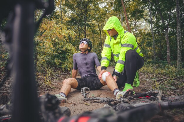 Acidente de btt e primeiros socorros: acidente de motociclista, lesões no joelho e perna, primeiros socorros para ajudar ciclista de montanha em acidente. equipe de primeiros socorros de atleta de mountain bike ferida durante acidente de corrida.