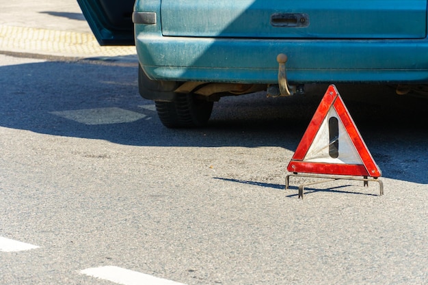 Acidente de carro Um carro de passageiros quebrado está na estrada após um acidente Sinal de trânsito de uma parada de emergência Seguro de acidentes na estrada