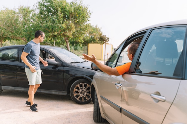 Acidente entre dois carros com 2 pessoas ao ar livre