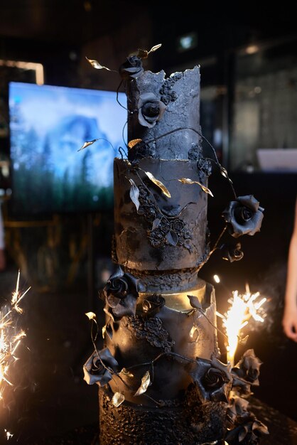 Acima de velas acesas, fogos de artifício ficam em um bolo e uma mão paira sobre ele