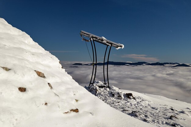 Acima do mar de neblina nas montanhas de inverno Dia ensolarado em montanhas dos Cárpatos cobertos de neve Ucrânia Nuvens acima do céu claro