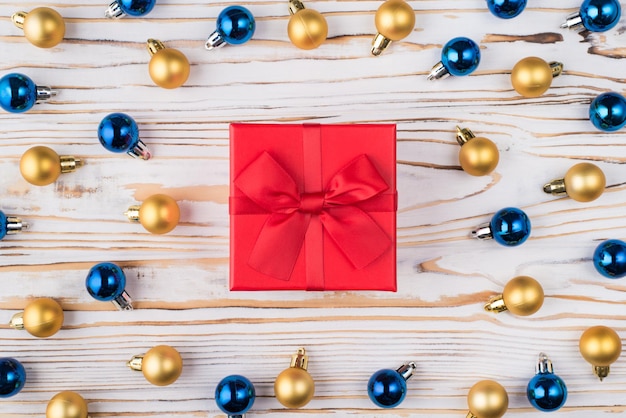 Acima em cima, close-up, ver a foto de um lindo pequeno presente com um laço fofo e muitas bolas de natal coloridas