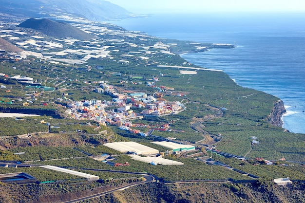 Acima vista da paisagem de plantações de frutas fora da cidade de La Llanos La Palma Espanha Colinas cênicas tropicais mar e oceano agricultura e arquitetura edifícios da cidade Viajar no exterior para destino turístico