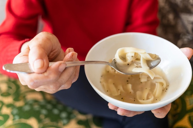 Acima vista da tigela com sopa de macarrão na mão