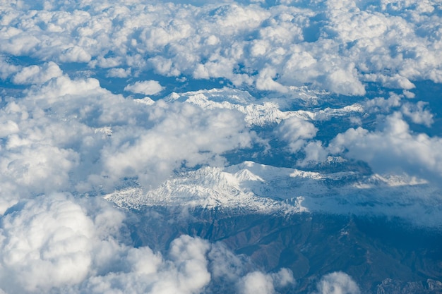 Acima vista das nuvens sobre montanhas rochosas cobertas de neve