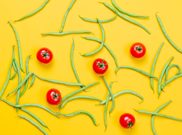 Acima vista em tomates e feijão verde em fundo amarelo