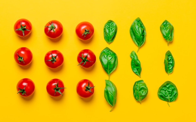 Acima vista em tomates e manjericão em fundo amarelo