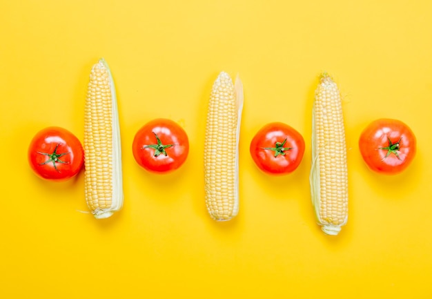 Acima vista em tomates e milho em fundo amarelo