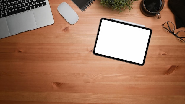 Acima vista tablet digital, xícara de café e computador portátil na mesa de madeira.
