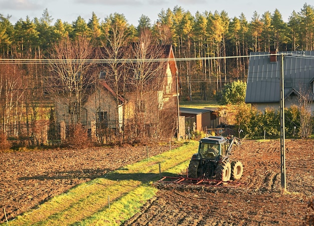 Ackerschlepper auf dem Bodenfeld beschäftigt ländlicher Landschaftsbauer, der während der goldenen Stunden arbeitet