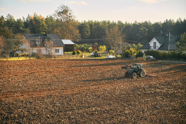 Ackerschlepper auf dem Bodenfeld beschäftigt ländlicher Landschaftsbauer, der während der goldenen Stunden arbeitet