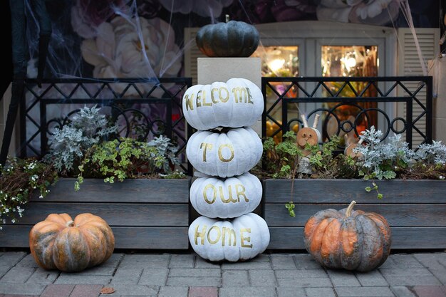 Acogedor y aterrador porche de la casa con calabazas naranjas y blancas en otoño Diseño de Halloween