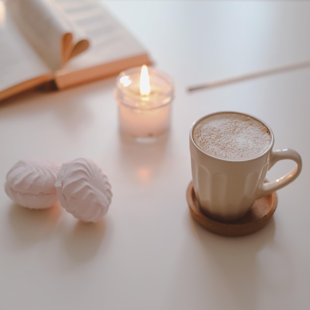 Acogedor bodegón con una taza de café vela libro abierto sobre un fondo soleado