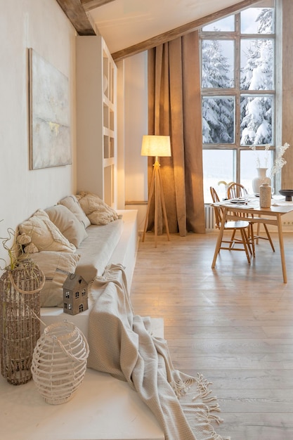 Acogedor y cálido interior de un elegante chalet de campo con una enorme ventana panorámica con vistas al bosque de invierno, decoración de madera de planta abierta, colores cálidos y un hogar familiar