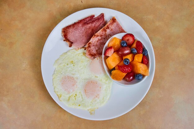 Acogedor desayuno americano con frutas frescas y jamón en ángulo de arriba