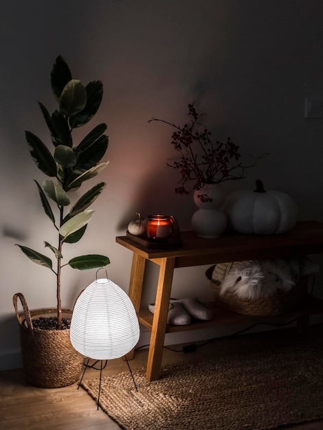 Acogedor interior nocturno un jarrón con ramas de arándano una almohada de calabaza una vela en un banco de roble