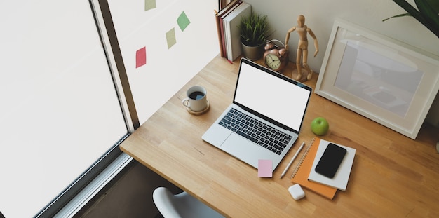 Acogedor lugar de trabajo con computadora portátil con pantalla en blanco abierta