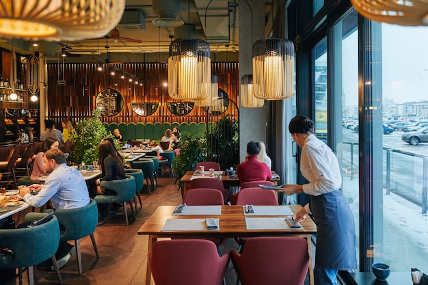 Foto acogedor restaurante con gente y camarero.