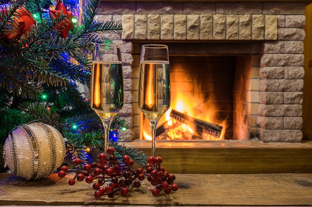 Acogedora chimenea. Champagne vino antes de árbol de Navidad decorado juguetes y luces de Navidad en casa de campo.