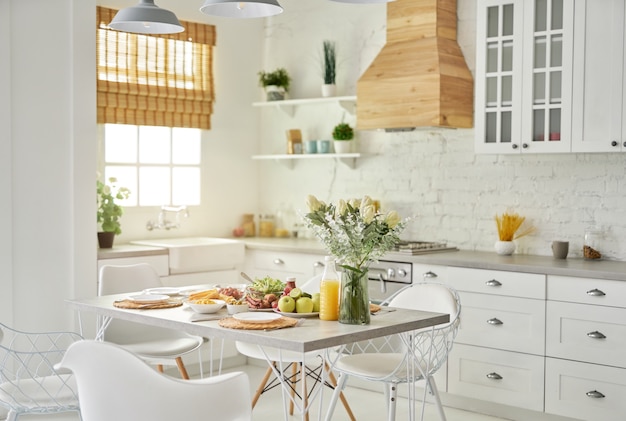 Acogedora cocina moderna cocina blanca brillante interior con jarrón de madera y detalles en blanco con flores