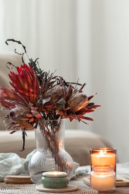 Acogedora composición casera con velas y ramo de protea.