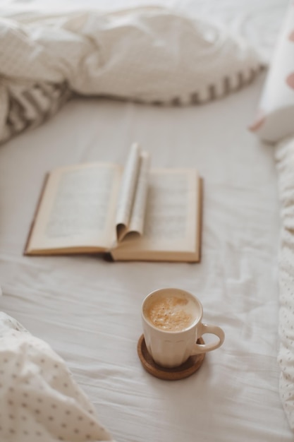 Acogedora composición matutina con una taza de café y un libro en la cama