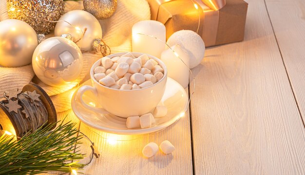 Una acogedora composición navideña con una taza de café y juguetes de árbol de Navidad iluminados por una guirnalda. El concepto de Navidad y año nuevo.