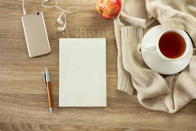 Acogedora composición de otoño con cuaderno y taza de té.