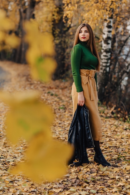 Acogedora y elegante niña caminando en el parque otoño