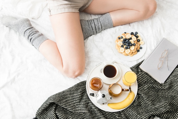 Acogedora escena de desayuno en la cama en un fin de semana con café y gofres