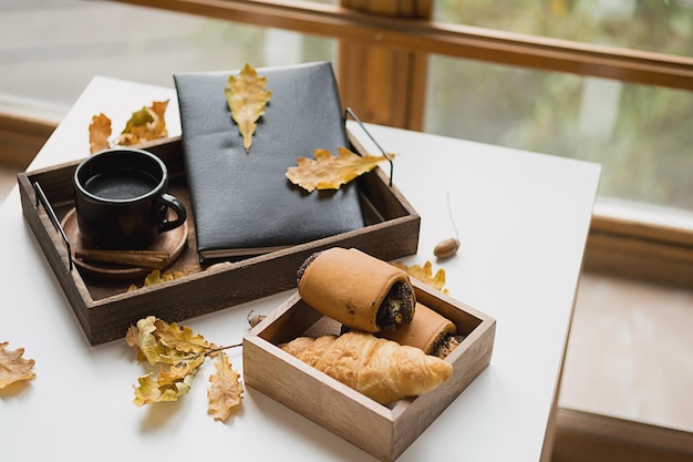 Acogedora mañana de otoño en casa Libro de taza de café y hojas de otoño en bandeja de madera