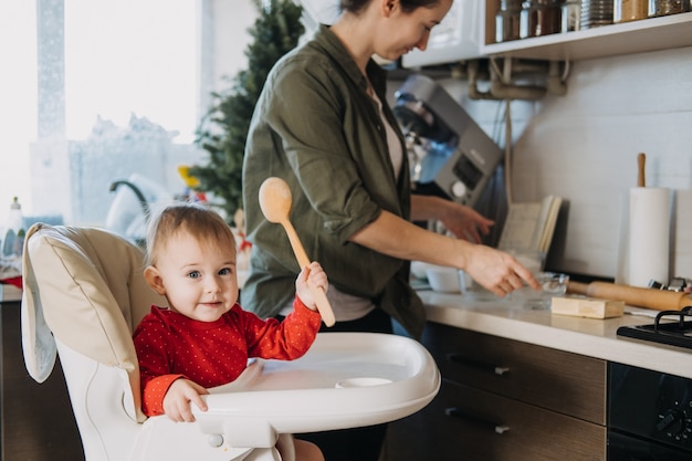 Acogedora Navidad en casa, preparación familiar, postre navideño, madre y bebé, niño pequeño, hija jugar