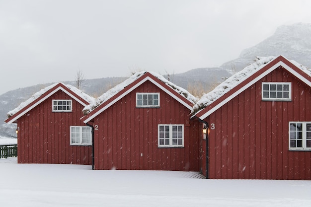 Acogedoras casas noruegas rojas en invierno bajo la nieve