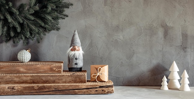 Acogedoras decoraciones navideñas sobre un fondo gris Caja de regalo de elfo de adorno de corona y árboles de Navidad blancos
