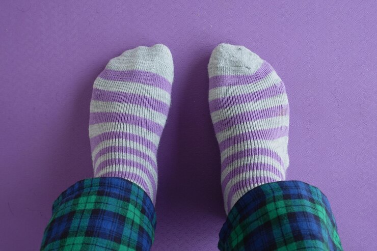 Foto acogedores calcetines a rayas en un piso púrpura con pantalones a cuadros
