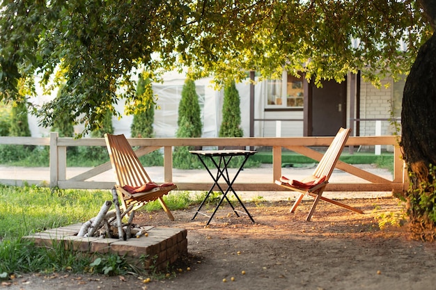 Acolhedor pátio interior com mesa e espreguiçadeiras com lareira de pedra ao ar livre no jardim