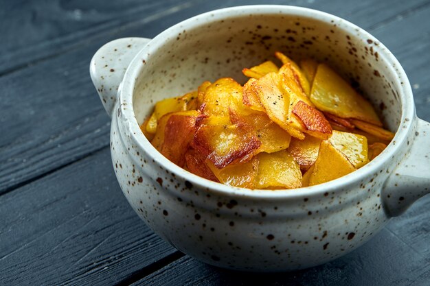 Acompanhamento apetitoso - batatas fritas com cebola servidas em uma tigela branca sobre uma superfície escura.