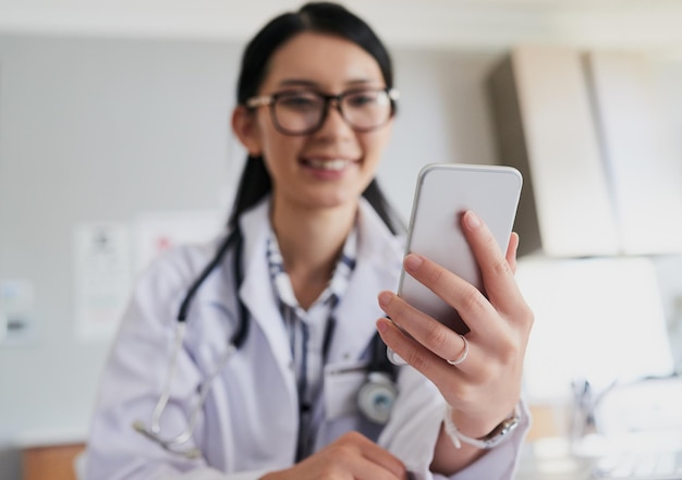 Foto acompanhando um paciente foto recortada de uma jovem médica enviando um texto enquanto trabalhava no hospital