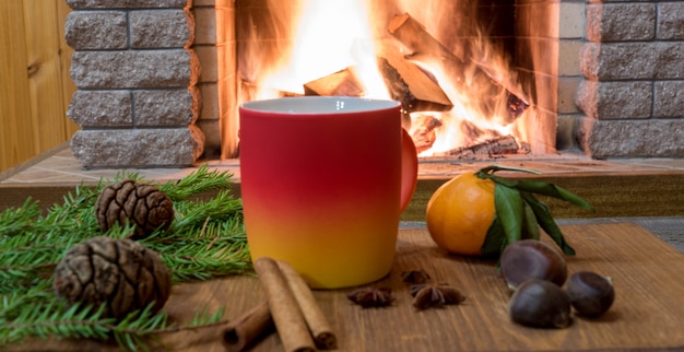 Aconchegante cena perto da lareira com caneca de bebida quente, tangarine, cones, nozes e canela sricks.