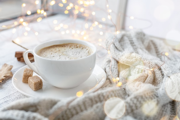 Aconchegante composição de outono com uma xícara de café, açúcar mascavo, cachecol de malha, guirlanda