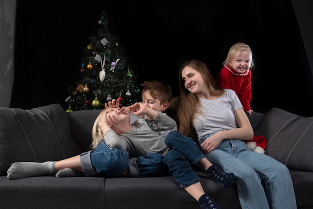 Aconchegante noite familiar - mãe e três crianças felizes e sorridentes no contexto da árvore de Natal.