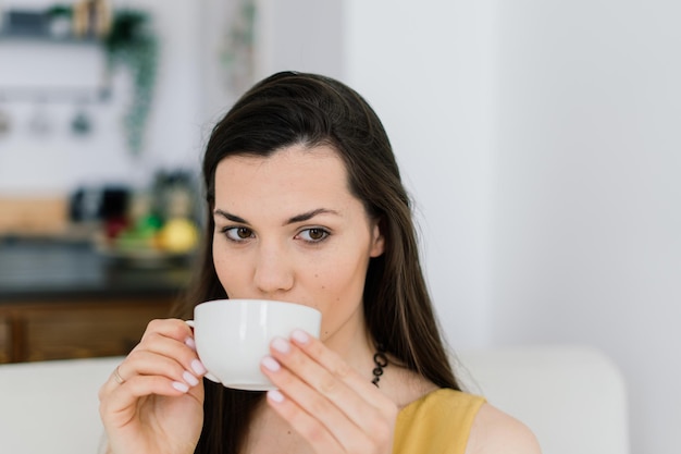 Aconchegante sala de estar feliz mulher sentada no sofá Mulher europeia gosta de fim de semana preguiçoso ou férias