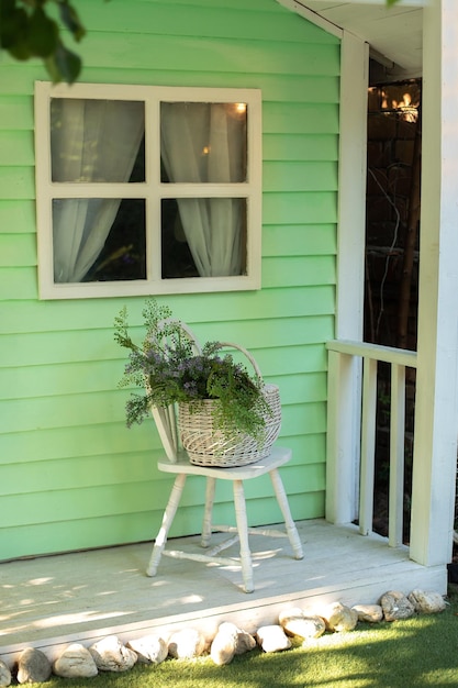 Aconchegante terraço em casa com cadeira e cesta com flores. Decoração de outono elegante na varanda da frente da casa.