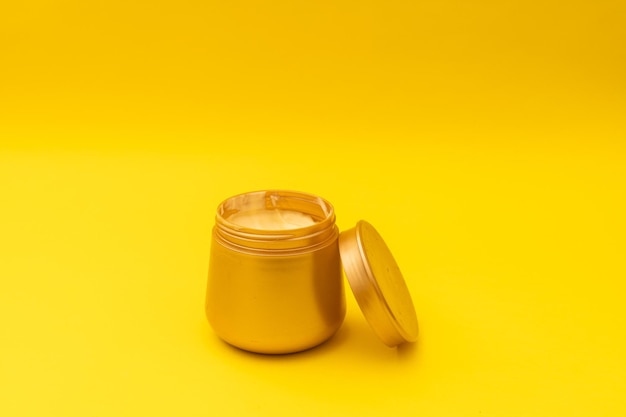 Acondicionador de cabello en un frasco dorado sobre un fondo amarillo una foto promocional de un producto para el cuidado