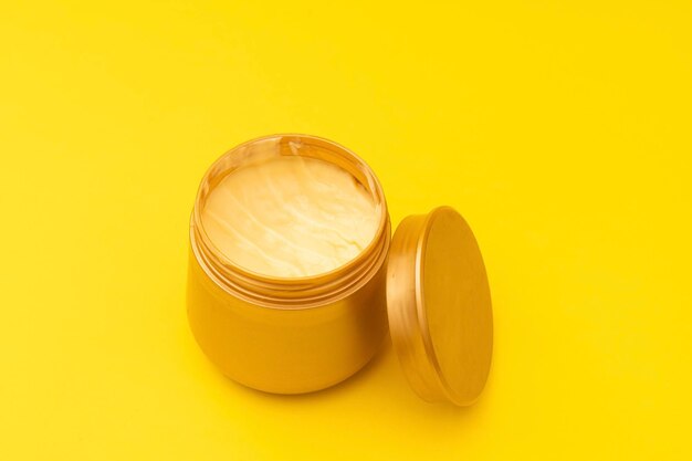 Acondicionador de cabello en un frasco dorado sobre un fondo amarillo una foto promocional de un producto para el cuidado