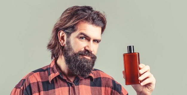 Acondicionador de champú para hombres Cuidado experto para cabello exigente Recipiente de plástico con champú Hombre guapo joven aplicando loción de crema El hombre sostiene una botella de champú o gel de ducha