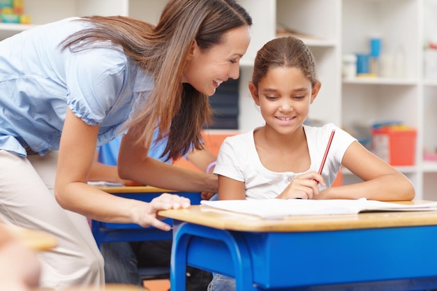 Aconselhamento educacional e professor com aluno na sala de aula para aprender conhecimento e estudar Ajuda feliz e educadora fala com a menina para ajuda na lição na escola para bolsa de estudos