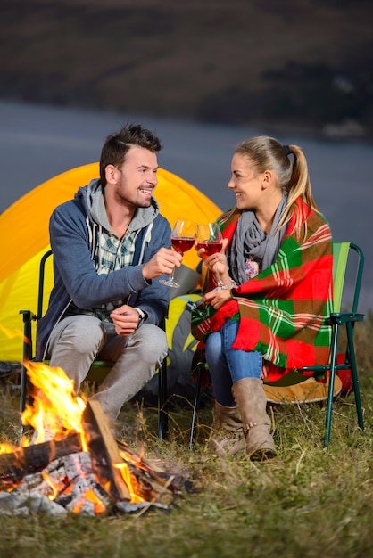 Acople perto de um fogo ao acampar bebendo o vinho junto.